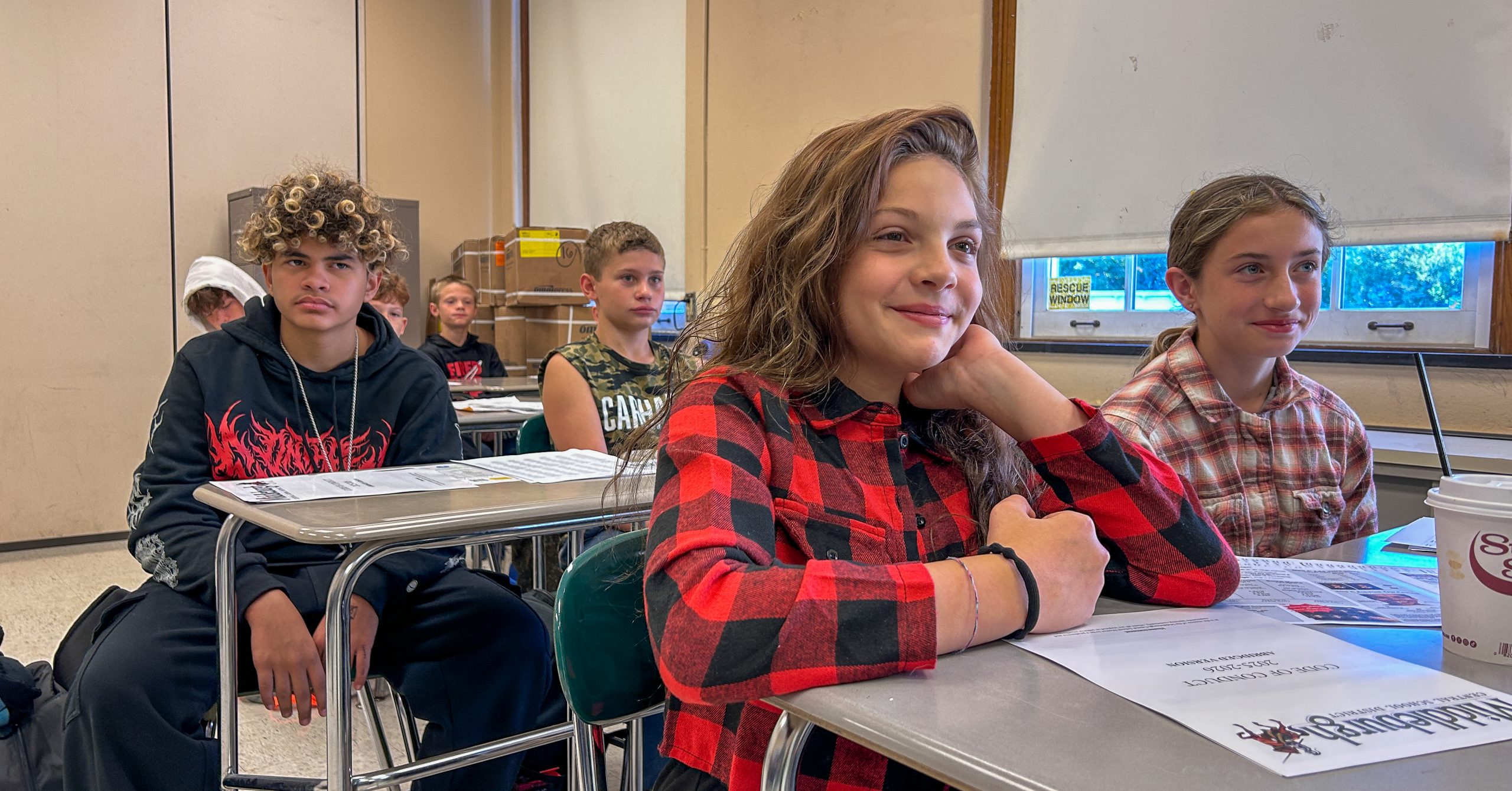 Junior high school students sitting at desks in classroom.