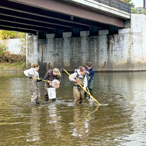 Teen in river with buckets and nets.