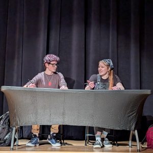 Two teens rehearse on stage.