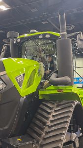 Student sits in cab of giant tractor.