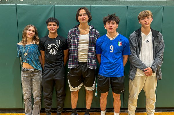 Five high school students stand together in gymnasium.
