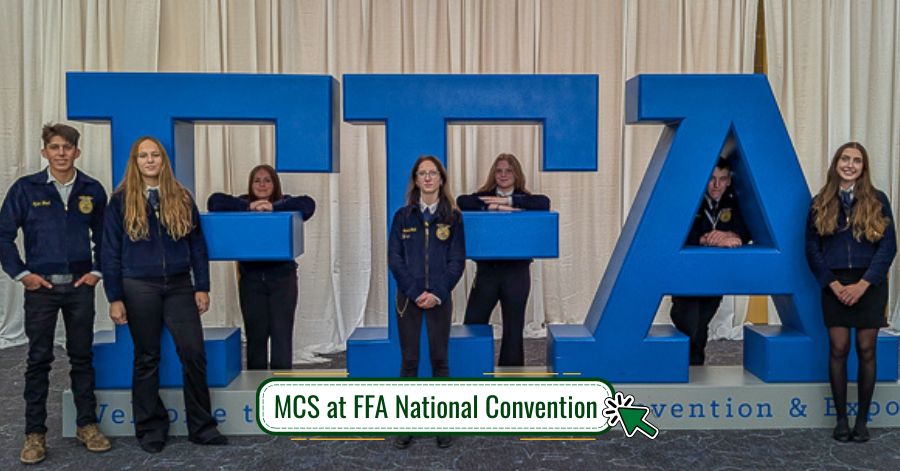 Seven teens wearing MCS FFA jackets stand next to FFA National Convention sign.