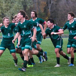 Members of the MCS Varsity Boys Soccer Team on the field. They have happy and triumphant expressions on their faces.