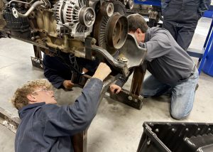 High school students work on an exposed engine.