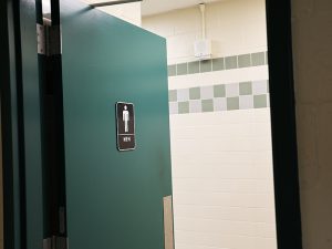 An open door leads to a men’s restroom, highlighting the interior tile work.