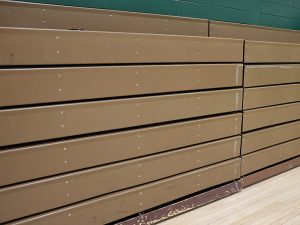 Bleachers in closed position against gym wall.