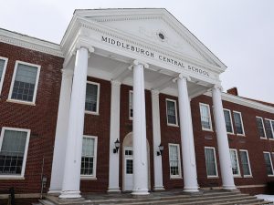 Front entrance of Middleburgh Central School, a red-brick building with white columns and a classical pediment.
