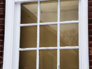 Old glass window with heavily chipped and peeling paint.