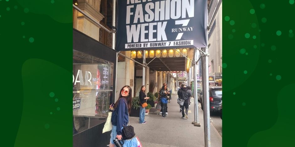 Teen, wearing sunglasses and carrying bags, stands near Fashion Week marque.