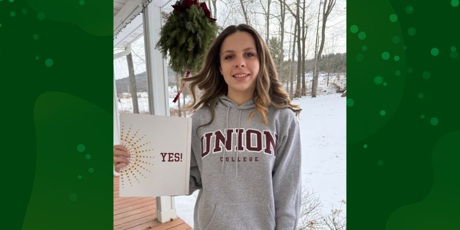 Student wearing a Union College sweatshirt holds a folder that says, "Yes."