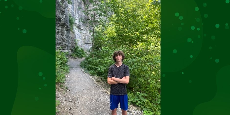 Teen stands in front of a waterfall.