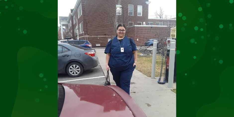 Nursing student in parking lot. Brick school in background.