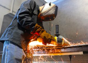 Sparks fly as a student wearing gloves and a helmet practices welding.