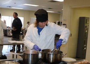 Teen practices culinary skills over large pots on stove.