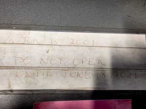 Handwritten instructions on the lid of a time capsule read, “June 18, 2001. Do not open until June 18, 2026.”
