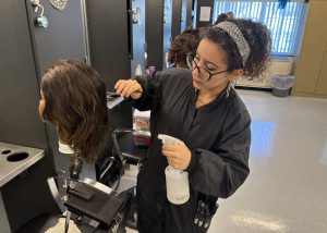 Teen practices cosmetology skills on a mannequin.