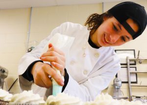Teen decorates a cake.