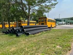 Drainage pipes staged near school bus garage.