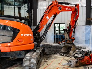 Excavator removing concrete inside bus garage.