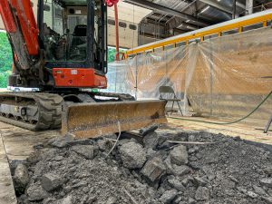 Bulldozer removing concrete inside bus garage.