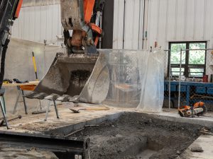 Excavator removing concrete inside bus garage.