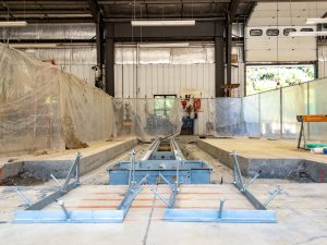 Vehicle lift components under installation inside a maintenance facility.
