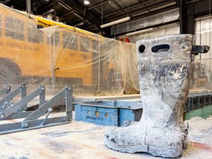 Mud-covered work boot next to construction lift inside a maintenance facility.