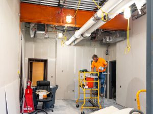 Worker prepping drywall inside a building under construction.