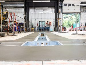 Copilot said: Transportation facility maintenance bay with vehicle lift installation in progress.