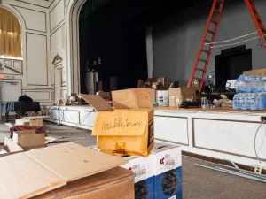 Auditorium stage area undergoing lighting and equipment upgrades. Box with the word "Middleburgh" written on it.