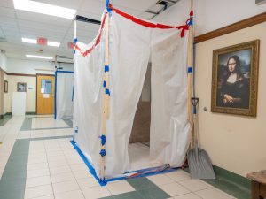 Construction containment area for balcony seating upgrades near a framed "Mona Lisa" reproduction.