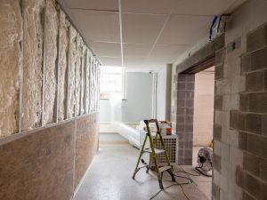 Hallway under renovation with exposed insulation and construction equipment.