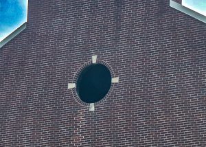 Exterior of brick school building with a round window removed.